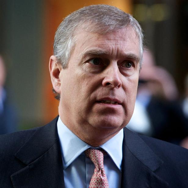 Ex-Prinz Andrew Mountbatten-Windsor mit grauen Haaren im Anzug und gemusterter Krawatte steht vor unscharfem Hintergrund.