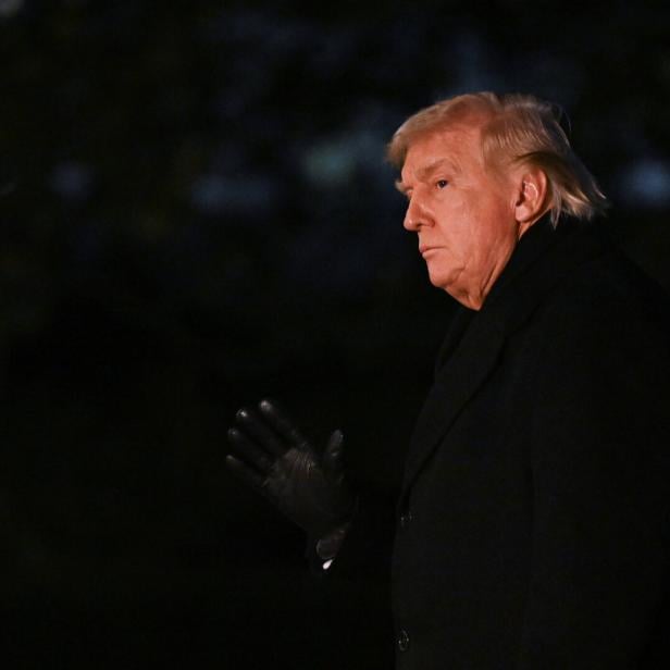 Donald Trump in dunklem Mantel und Handschuhen blickt zur Seite.