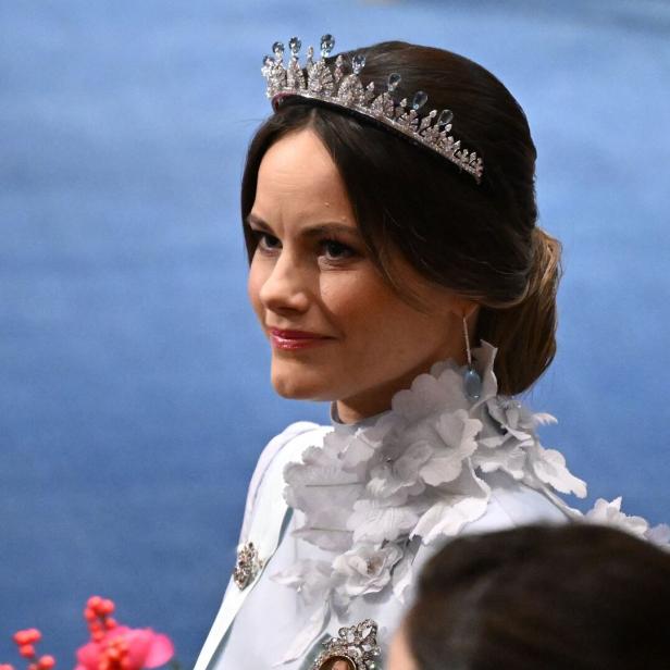 Prinzessin Sofia von Schweden mit Tiara und hellem Kleid mit Blumenapplikationen blickt zur Seite.