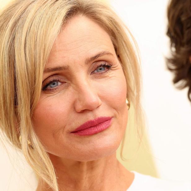 Cameron Diaz mit blonden Haaren und dezentem Make-up blickt freundlich nach vorne, im Hintergrund ist eine weitere Person teilweise sichtbar.
