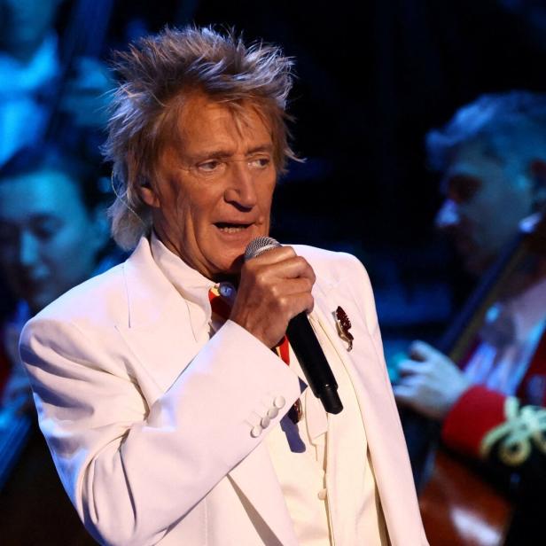Rod Stewart singt mit einem Mikrofon in der Hand vor einem Orchester.