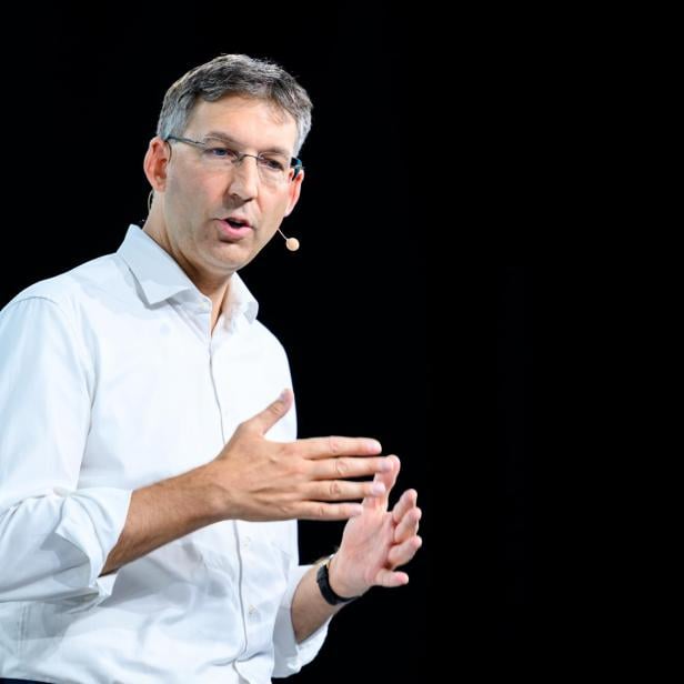 Markus Figl mit Brille und weißem Hemd gestikuliert vor einem schwarzen Hintergrund.