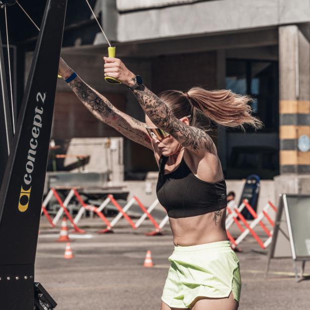 Frau trainiert an einem Ski-Ergometer im Freien bei sonnigem Wetter.