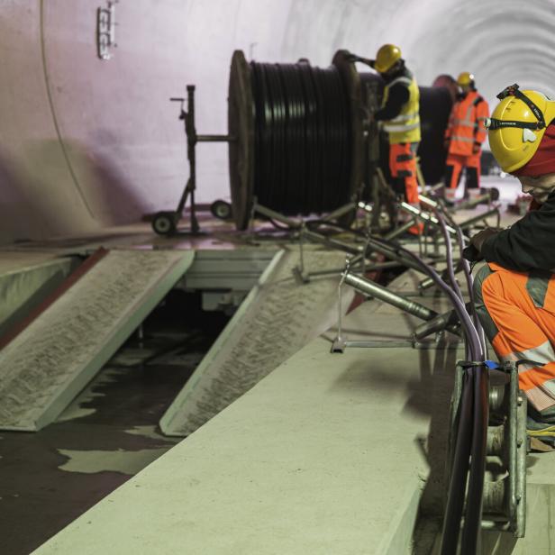 Arbeiter in orangener Kleidung bei den Arbeiten im Tunnel.