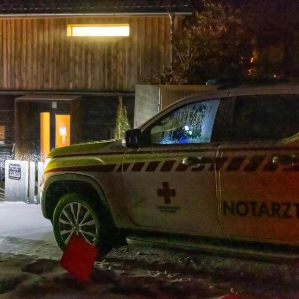 Ein Notarztfahrzeug steht nachts vor einem beleuchteten Gebäude im Schnee.