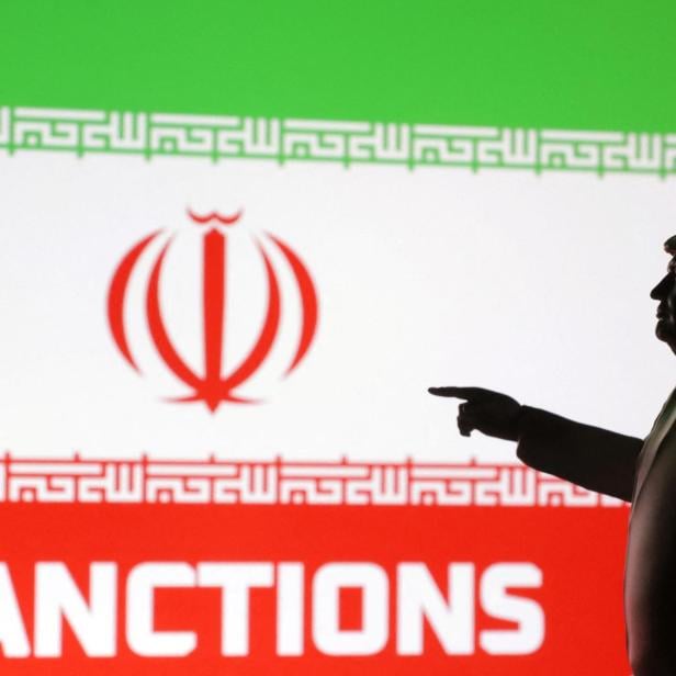 Eine Silhouette von Donald Trump deutet auf Sanktionen vor der iranischen Flagge.