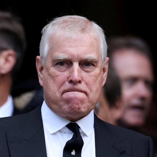 Ex-Prinz Andrew Mountbatten-Windsor trägt einen dunklen Anzug mit Krawatte und blickt ernst.
