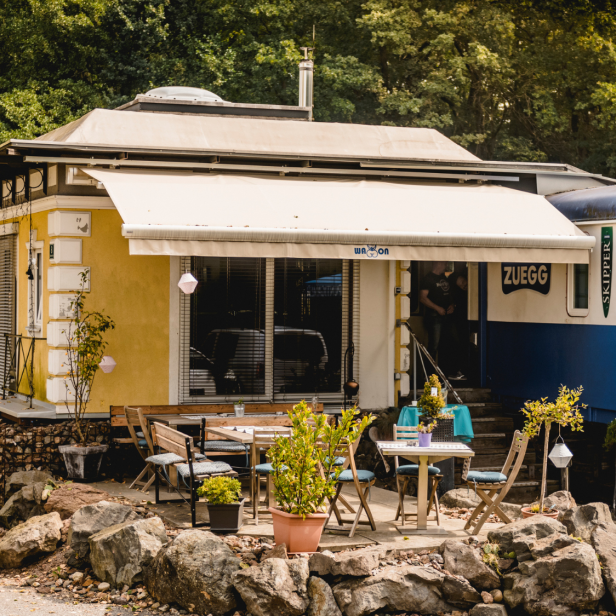 Ein gelbes Häuschen bei einem blauen Waggon 