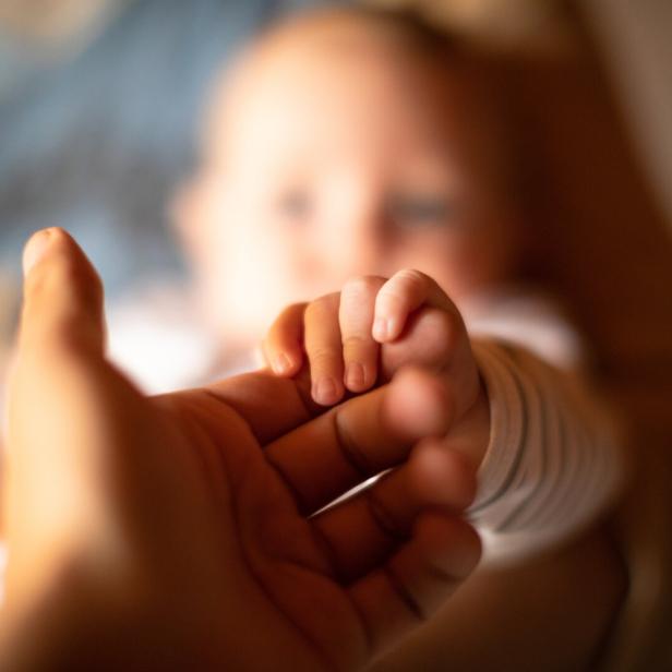 Hand holding newborn baby's hand