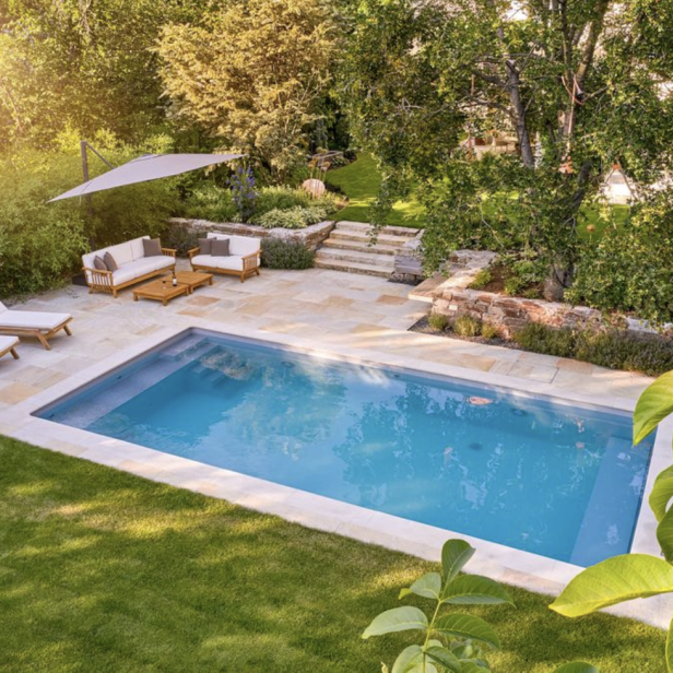 Ein Schwimmbecken im Garten mit einer Liege und einem Sonnenschirm.