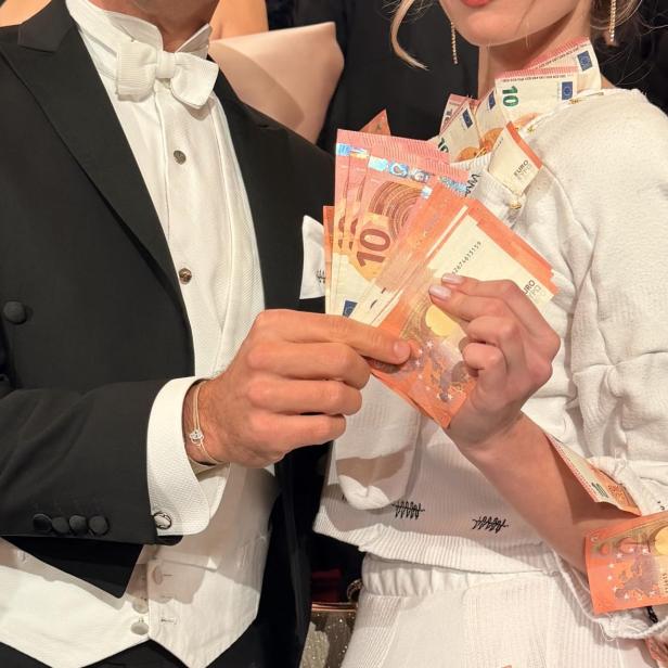 Max Weißenböck und seine Mitarbeiterin Joanna präsentieren beim Opernball ein Kleid, das mit 10-Euro-Scheinen geschmückt ist.