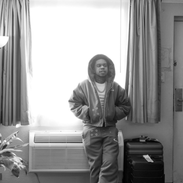 Mann mit Hoodie-Kapuze auf dem Kopf lehnt gegen Heizkörper am Fenster