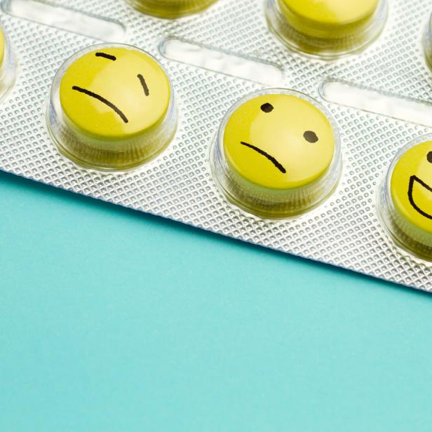 Yellow pills andfunny faces in a blister on a blue background.