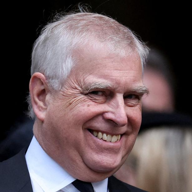 Andrew Mountbatten-Windsor lächelt mit grauem Haar und dunklem Anzug.