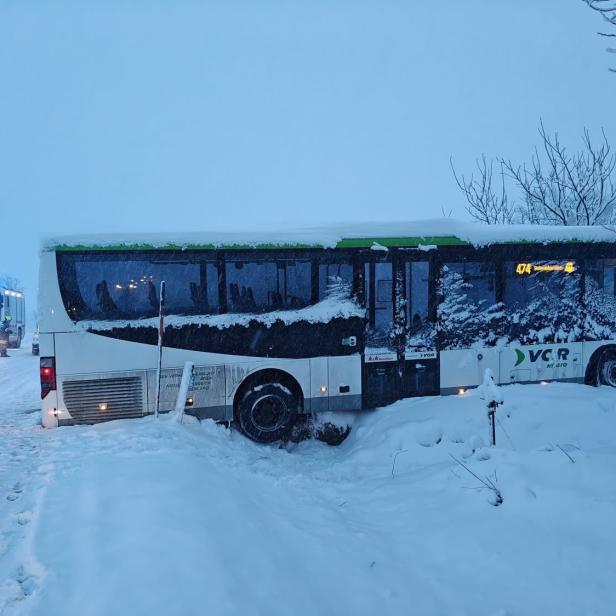 Ein Schulbus ragt senkrecht über den Straßengraben und in die dahinterliegende, schneebedeckte Wiese hinein.