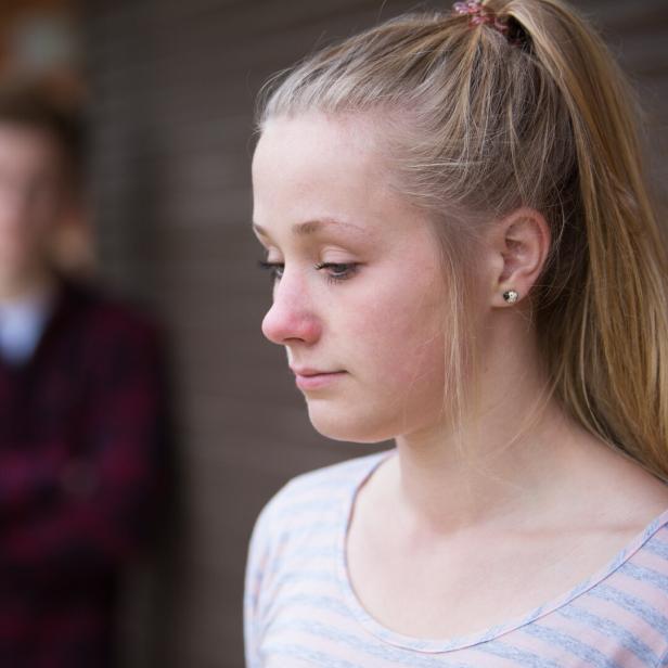 Ein Mädchen mit blondem Pferdeschwanz blickt traurig nach unten.