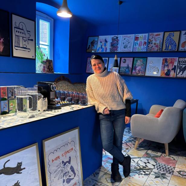 Mareike lehnt an ihrer Kaffee-Schank in der blauen Kaffee-Nische.
