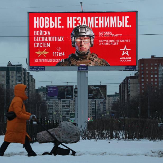 A woman walks past an advertising board, which promotes contract military service in the Russian army, in Saint Petersburg