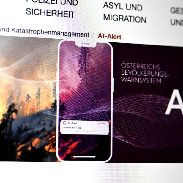 Ein Smartphone zeigt eine Warnmeldung vor einem Hintergrund mit brennendem Wald und dem Text „Österreichs Bevölkerungs-Warnsystem“.