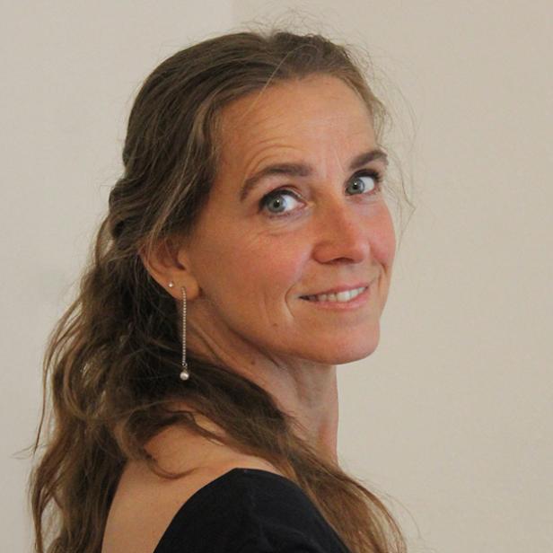 Eine Frau in einem schwarzen Oberteil, schaut über ihre Schulter 