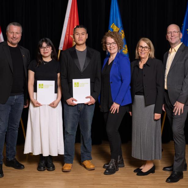 Mehrere Personen stehen vor einer Wand vor der auch die Flaggen von Vietnam, Österreich, Niederösterreich und der EU platziert sind und lächeln in die Kamera.