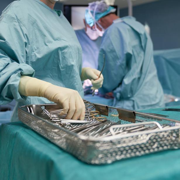 Chirurgisches Team in OP-Kleidung arbeitet mit sterilen Instrumenten an einem Operationstisch.