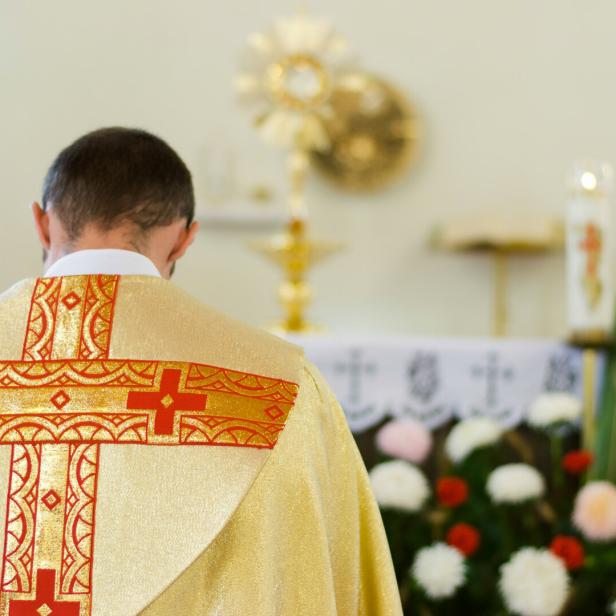 Priest of the Catholic Church in yellow clothes bows