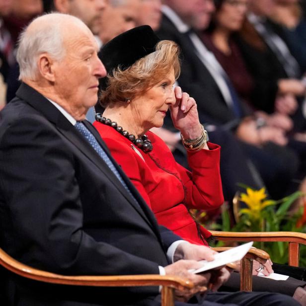 König Harald V. und Königin Sonja von Norwegen sitzen während einer Veranstaltung im Publikum.