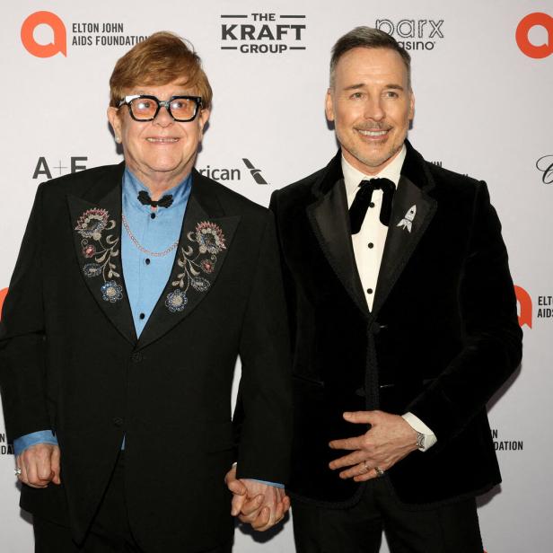 Elton John und David Furnish halten Händchen auf einem Event.