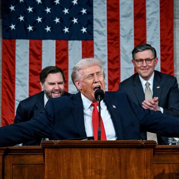 Ein Mann breitet seine Hände weit aus vor dem Hintergrund der amerikanischen Flagge