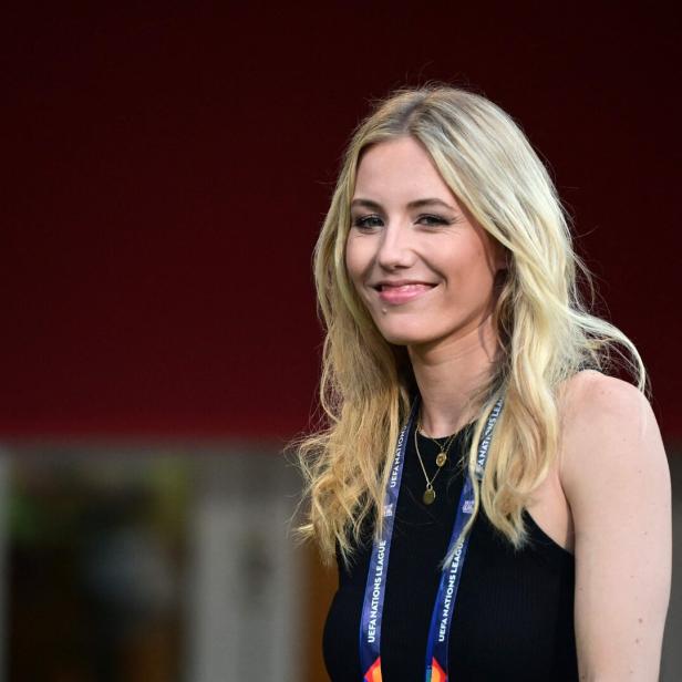 Laura Papendick mit langen blonden Haaren lächelt, trägt ein schwarzes Oberteil und ein UEFA Nations League Band um den Hals.