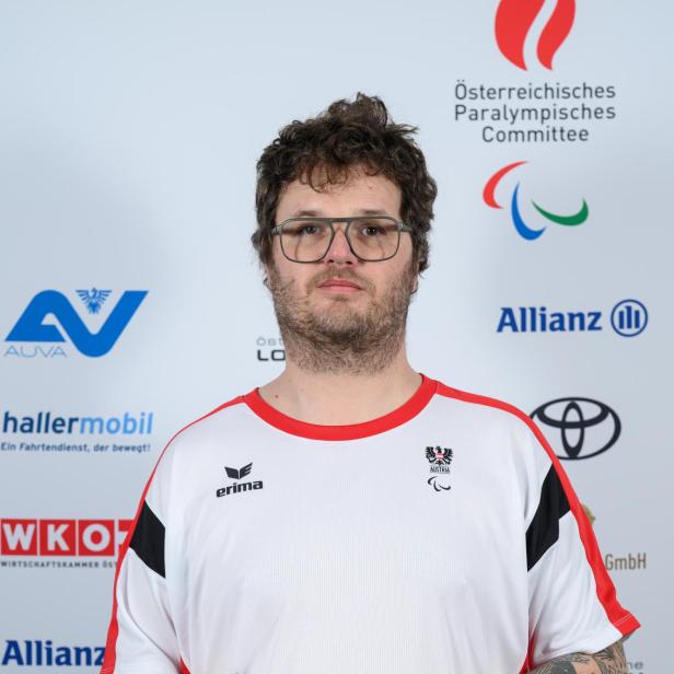 Markus Schmidhofer: Ein Mann mit Brille und tätowiertem Arm trägt ein weiß-rotes Sporttrikot mit österreichischem Paralympics-Logo.