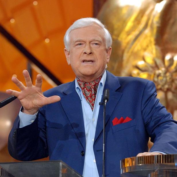 Hademar Bankhofer mit blauem Sakko gestikuliert vor einem Mikrofon auf einer Bühne.