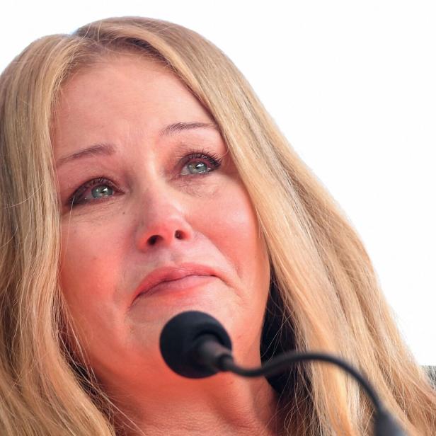 Christina Applegate mit Tränen in den Augen steht vor einem Mikrofon.