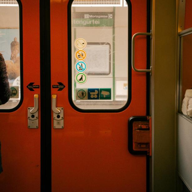 Fahrgast mit Rucksack steht in einer U-Bahn, Verbotsschilder an der Tür sind sichtbar.