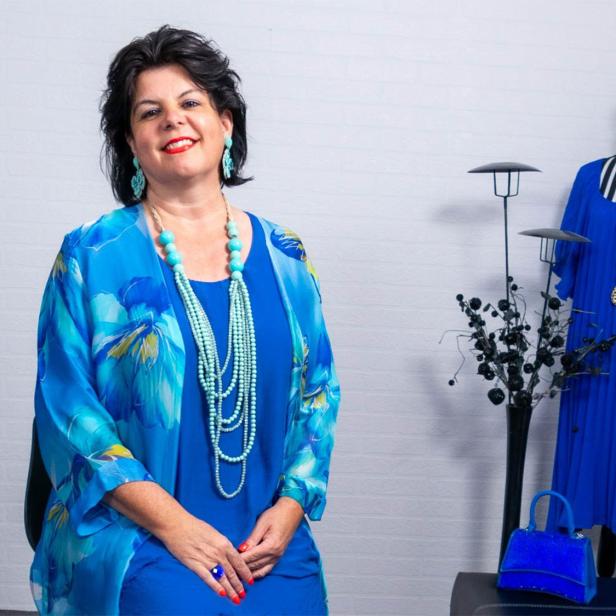 Eine brünette Frau in einem blauen Gewand vor einer weißen Wand