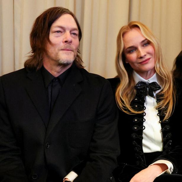 Norman Reedus und Diane Kruger sitzen nebeneinander, beide elegant in Schwarz gekleidet.