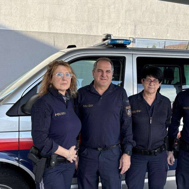 Vier Polizistinnen und Polizisten stehen in Uniform nebeneinander vor einem silbernen Polizeibus.