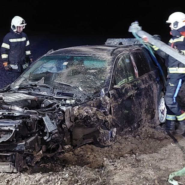Zerstörtes Auto und Feuerwehrleute
