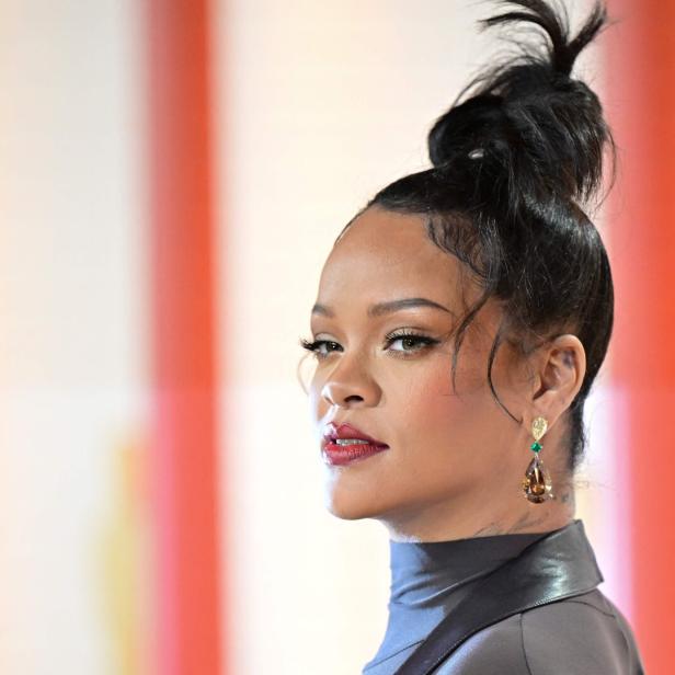 Rihanna mit hochgesteckten Haaren und auffälligen Ohrringen blickt zur Seite.