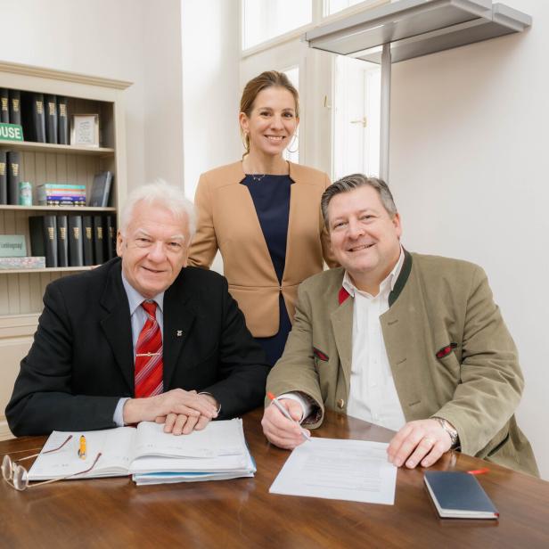 Eine Frau steht hinter zwei sitzenden Männern.