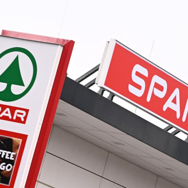 Ein SPAR-Schild mit dem bekannten grünen Baum-Logo ist an einem Gebäude angebracht.