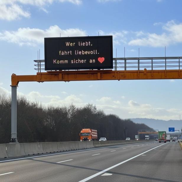 Ein Foto von der Autobahn und einer Anzeige darüber, auf der "Wer liebt, fährt liebevoll. Komm sicher an" steht.