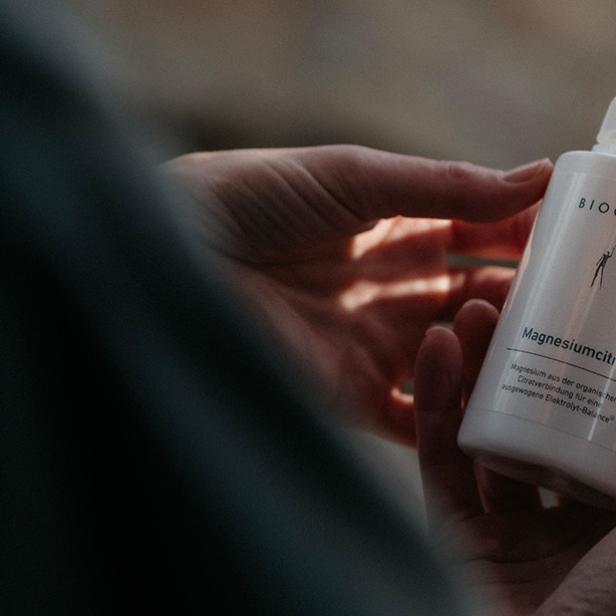 Eine Person hält eine weiße Packung mit Kapseln in der Hand.