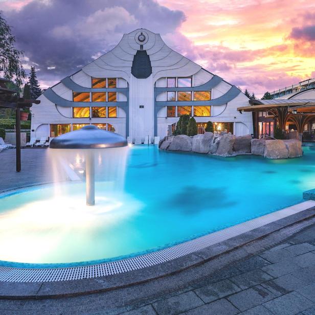 Ein Pool mit einem Brunnen und Wasserfeatures bei Sonnenuntergang, der eine ruhige und entspannende Atmosphäre schafft.