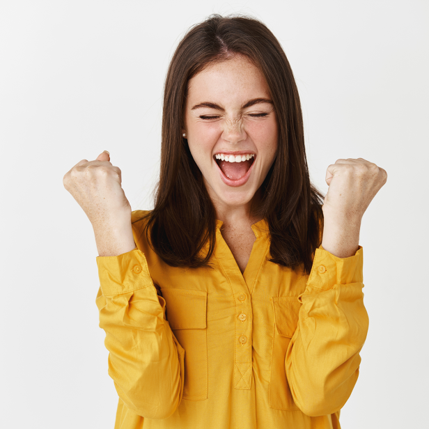 Eine Frau hebt lächelnd die Arme in die Luft.