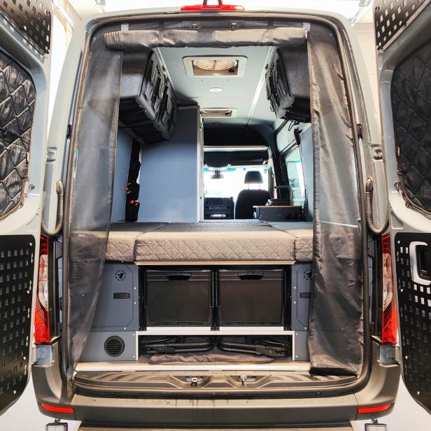Blick in den modular ausgebauten Innenraum eines Mercedes Sprinter Campervans mit Stauraum.