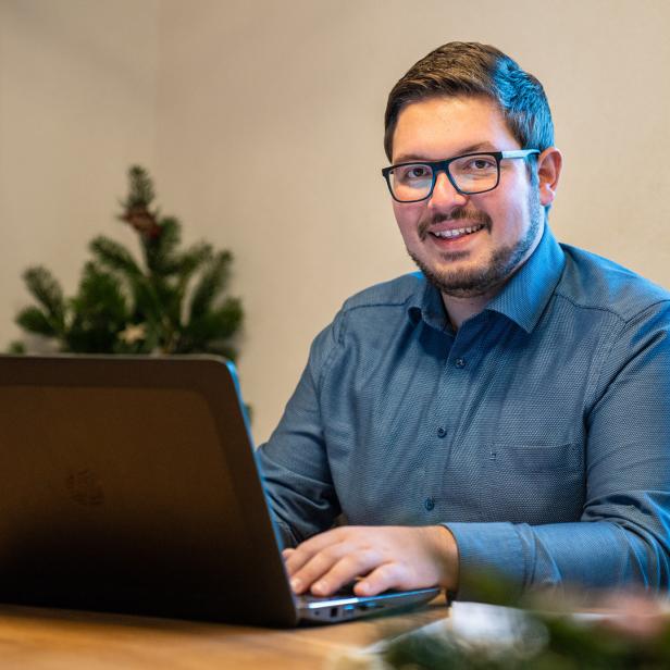 Ein Mann mit Brille und Bart sitzt an einem Laptop 