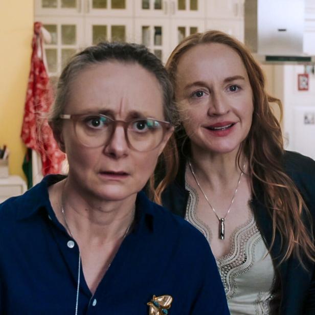 Szene aus "So haben wir dich nicht erzogen": Gerti Drassl und Brigitte Hobmeier, erstere mit Brille und besorgtem Blick, die andere lächelnd, stehen in einem Raum.