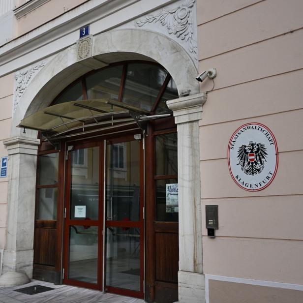Eingang eines Amtsgebäudes mit dem Wappen der Staatsanwaltschaft Klagenfurt an der Wand.
